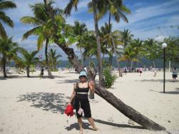 Joann holds a tropical drink next to palm tree at Cayo Levantado.jpg