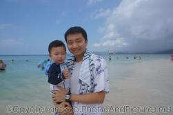 Darwin is held by Daddy standing in beach waters at Cayo Levantado .jpg